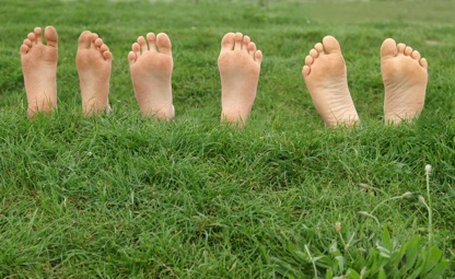Leuten liegen auf einer Wiese, nur die nackten Füße sind zu sehen.