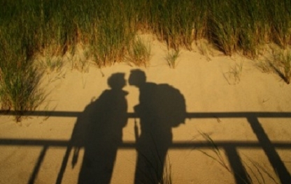 Zwei Schatten im Sand, die sich küssen